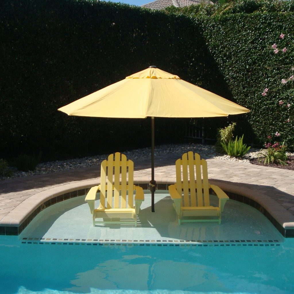 Deep-end sun shelf with a yellow umbrella and two in-water Adirondack chairs