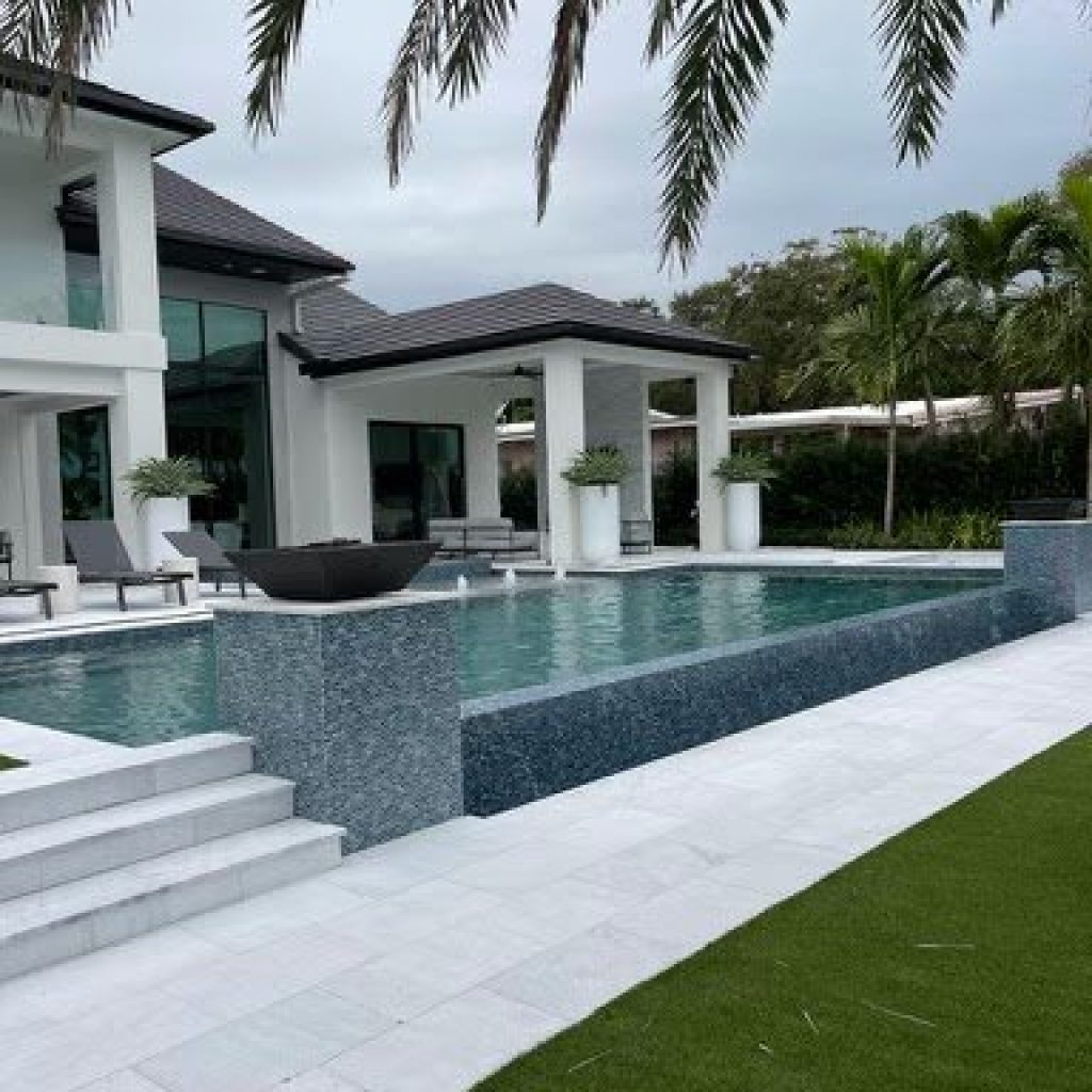Modern home with a glass-tile raised spa wall, fire bowls and wide pool entry steps