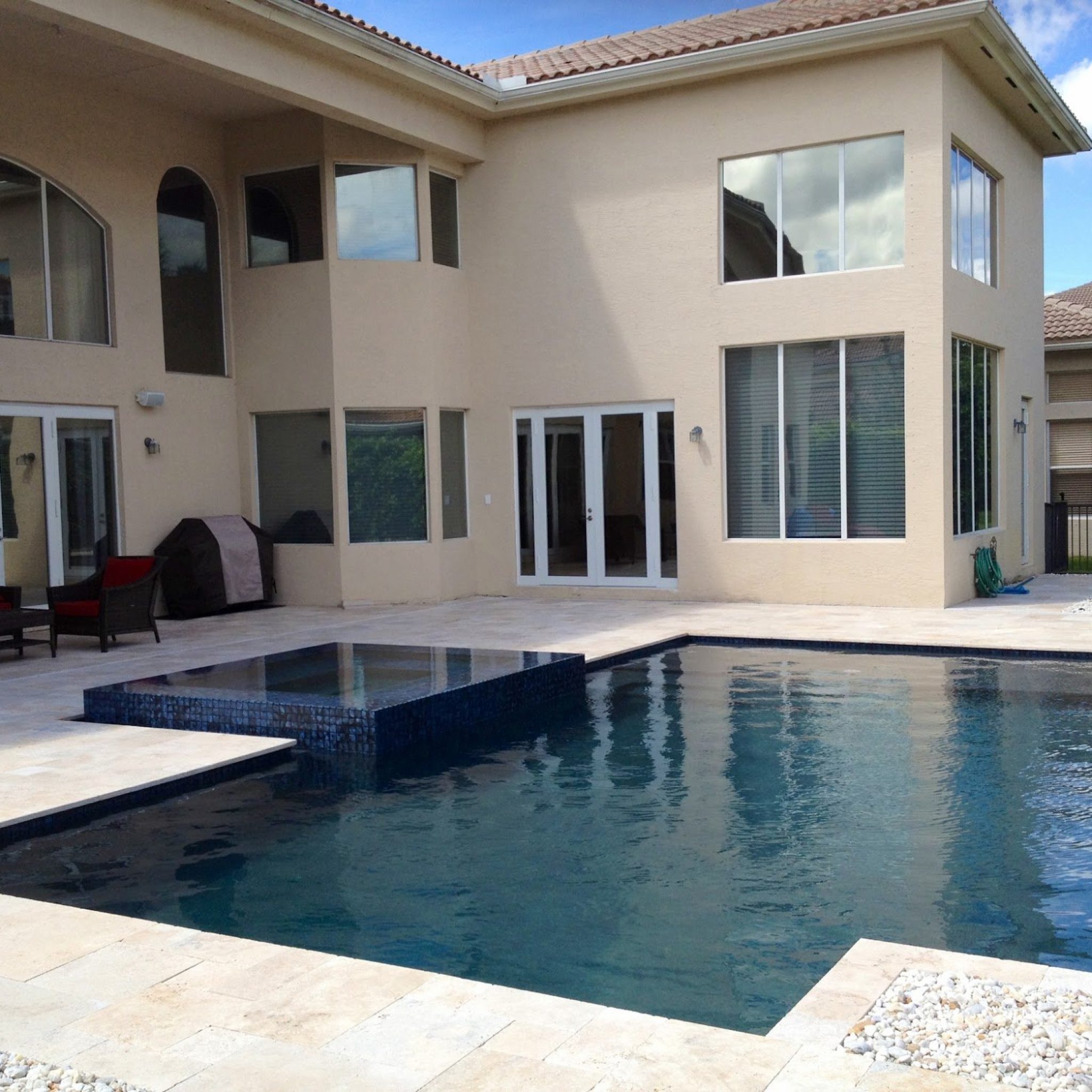 Pool with Ocean Blue Pebble Sheen finish and a raised spa beside a two-story home