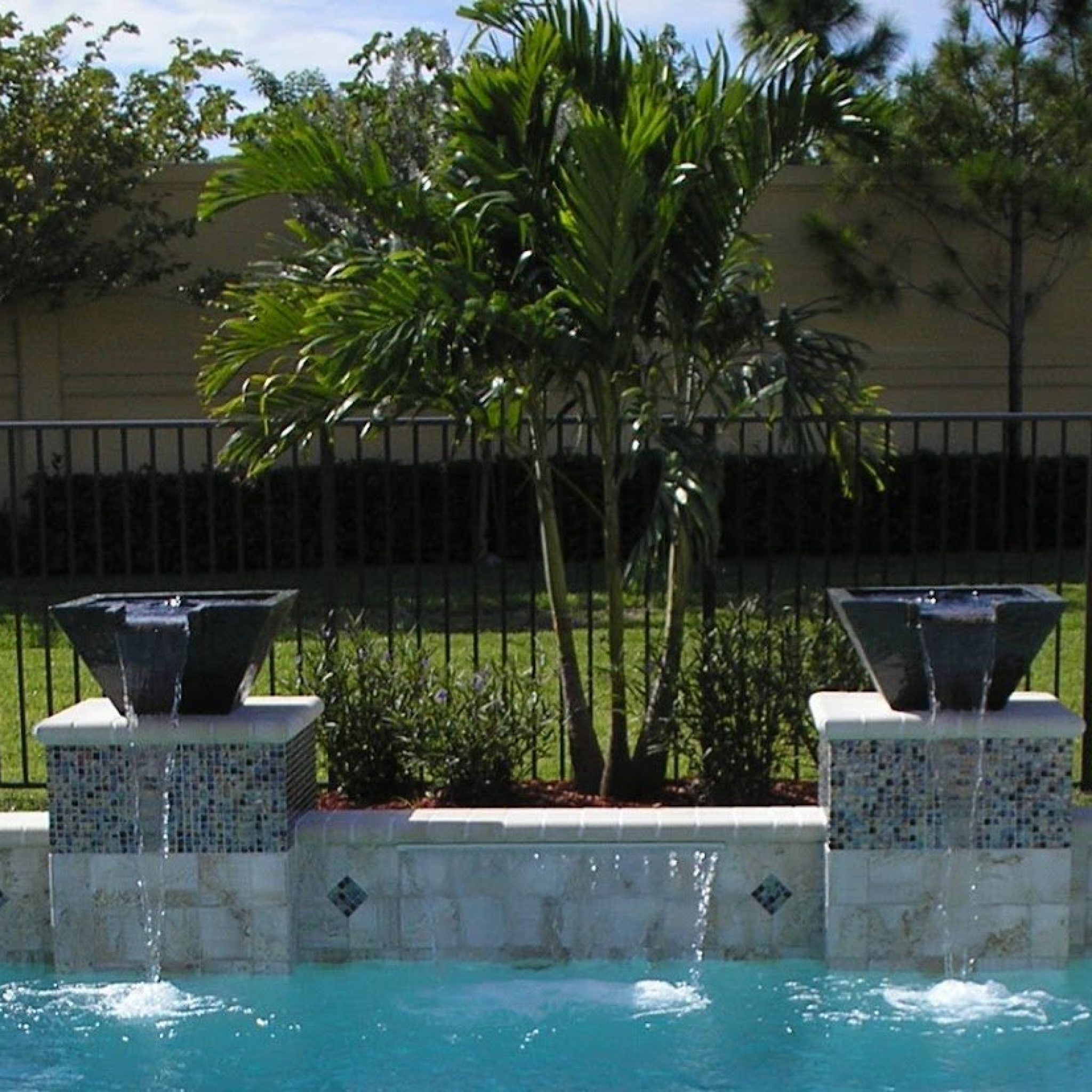 Pool with twin fire bowls and sheer descent waterfalls on a tiled raised wall