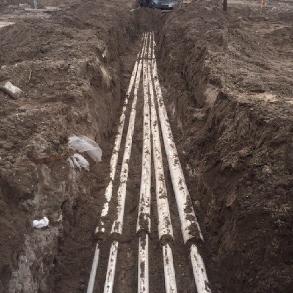 Pool plumbing lines installed in an excavated trench during pool construction