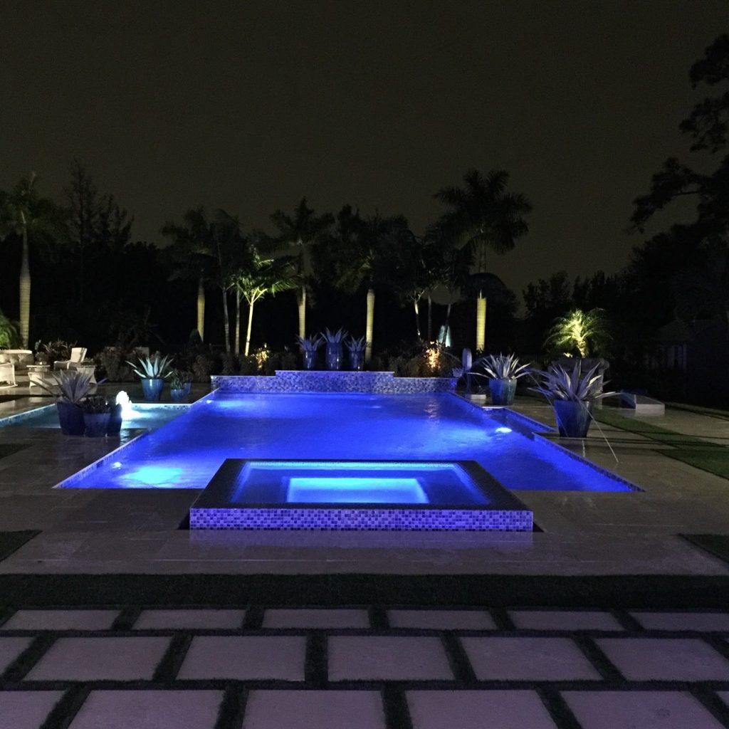 Pool and spa lit with light blue LED lights at night