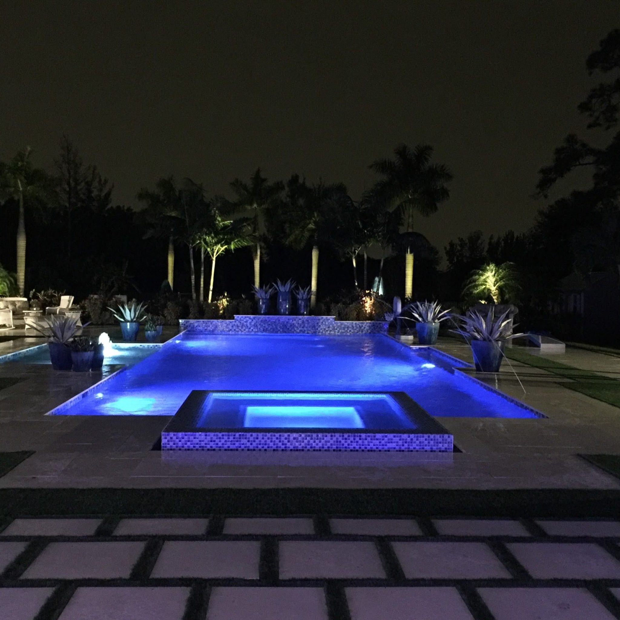 Pool and spa lit with light blue LED lights at night