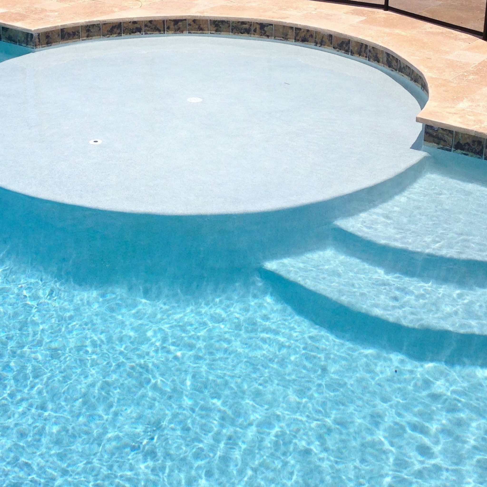 Rounded pool sun shelf with curved offset entry steps and travertine coping