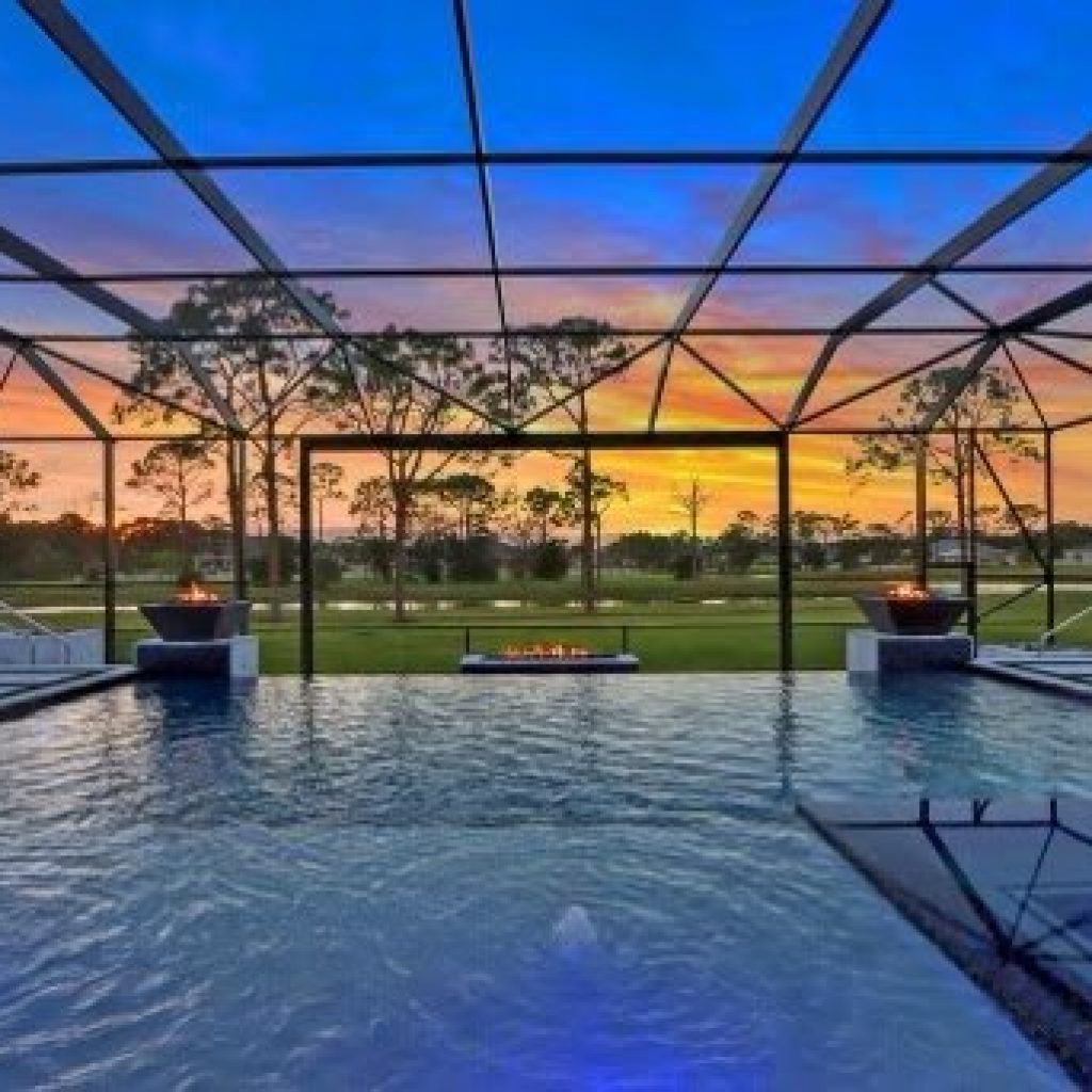 Screened pool enclosure at sunset with fire bowls along the pool edge